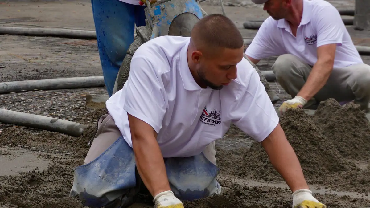 Concrete slab cost example: workers leveling a freshly poured concrete slab
