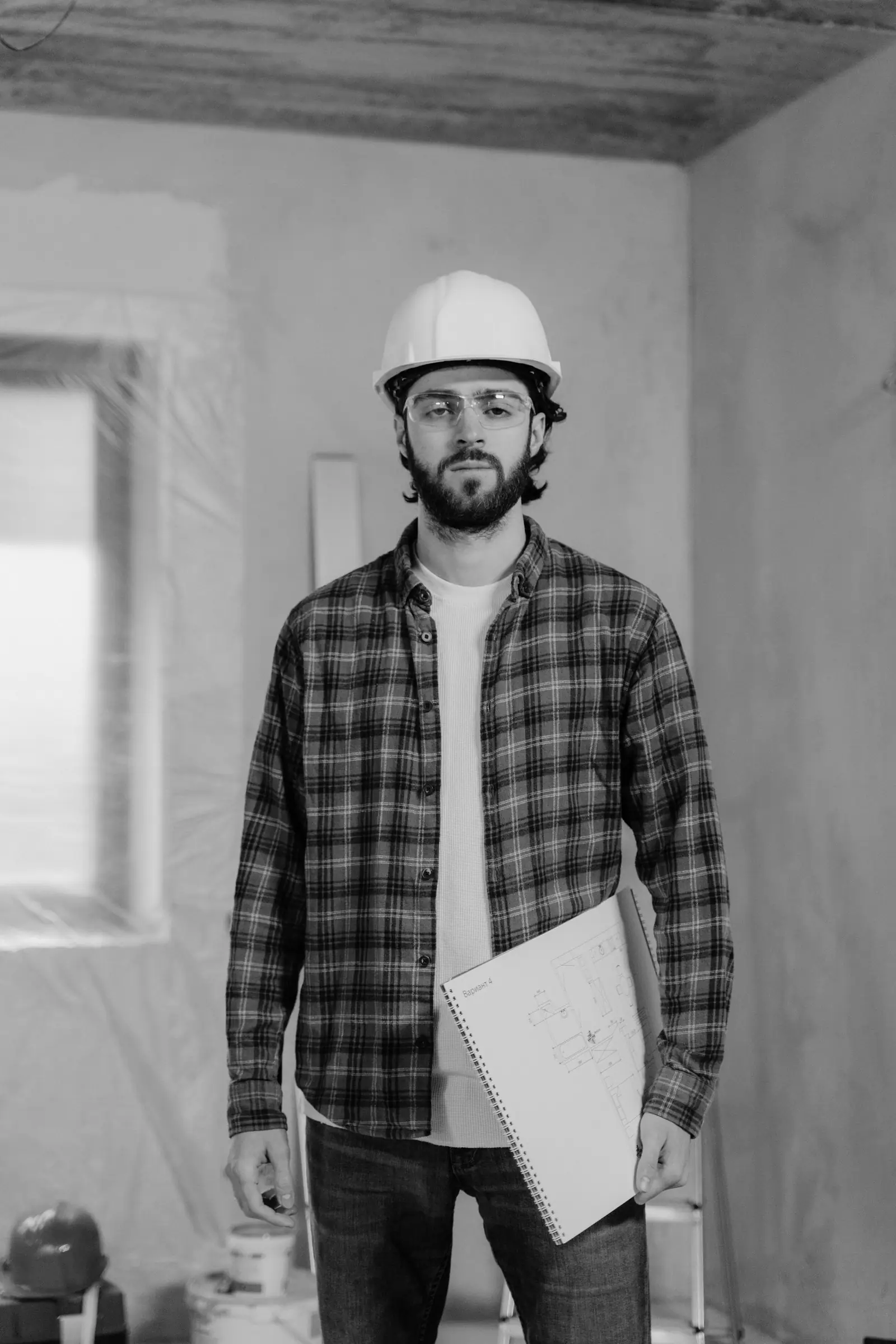Contractor in a white hard hat holding project plans on a renovation site