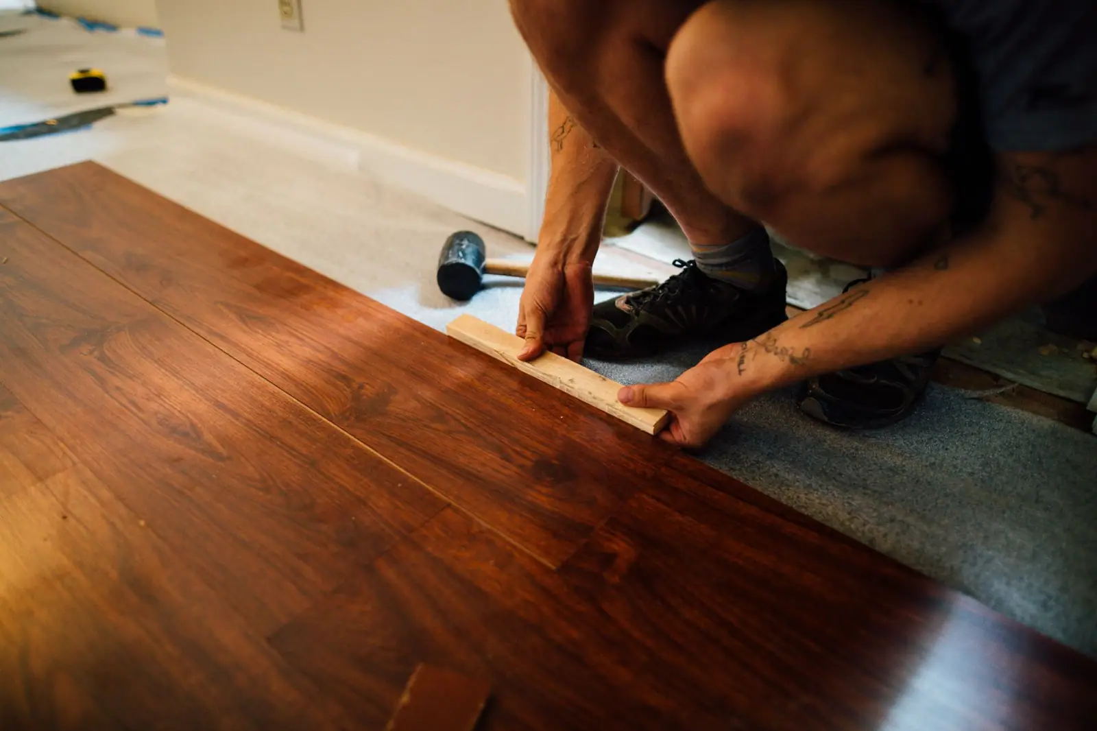 Installer fitting a wood-look laminate plank into place on a floor