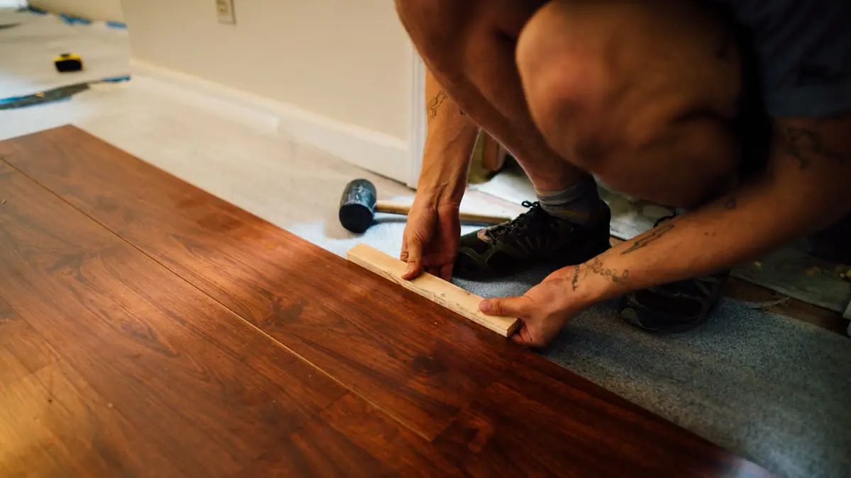Flooring installation cost: installer fitting a wood-look laminate plank