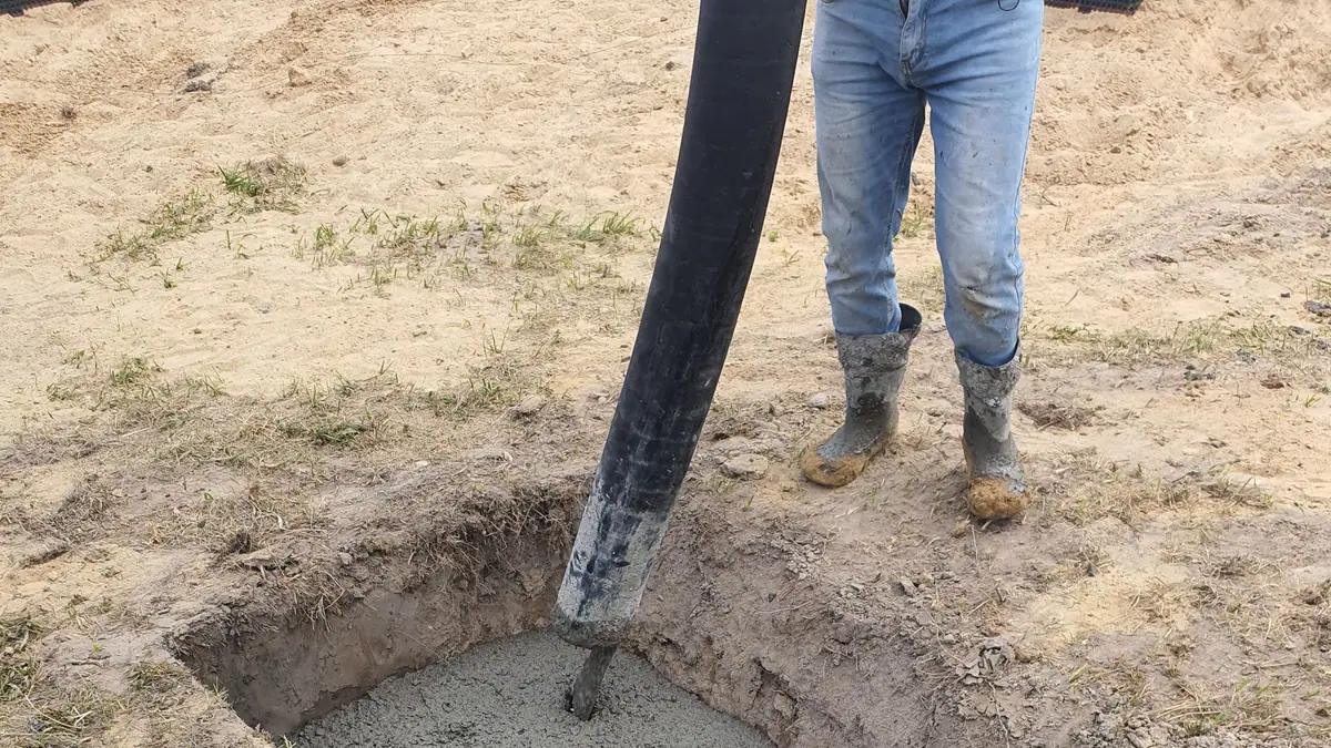 French drain cost: excavated trench with fresh concrete and steel rebar at a building site