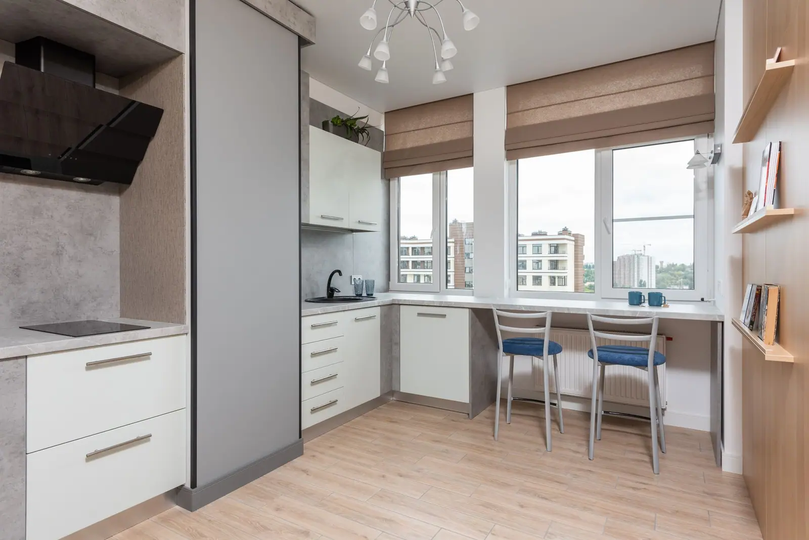Compact apartment kitchen with flat-panel cabinets, a window desk and plank flooring