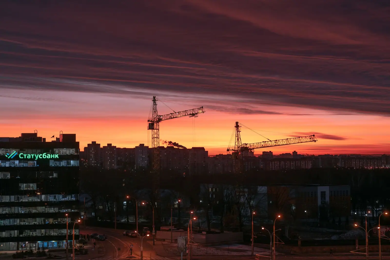 Construction cranes above a city skyline at dusk