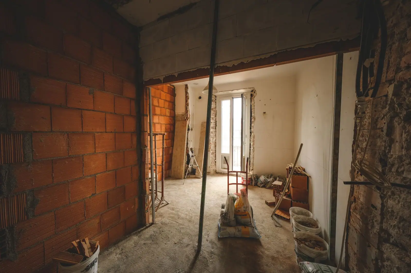 Gutted room with exposed brick walls and building materials during a major renovation