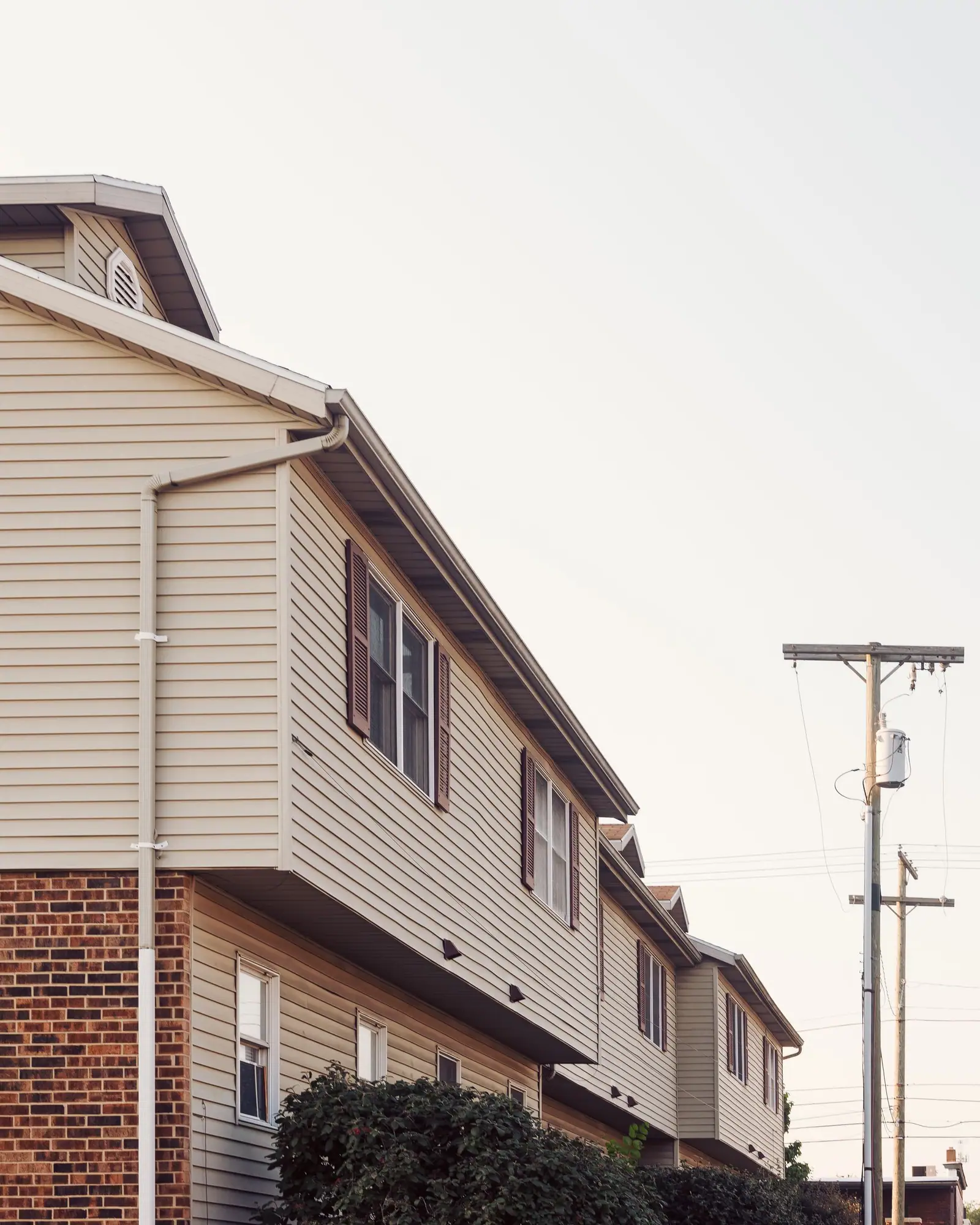 Row of two-story townhouses finished in beige horizontal lap siding over brick
