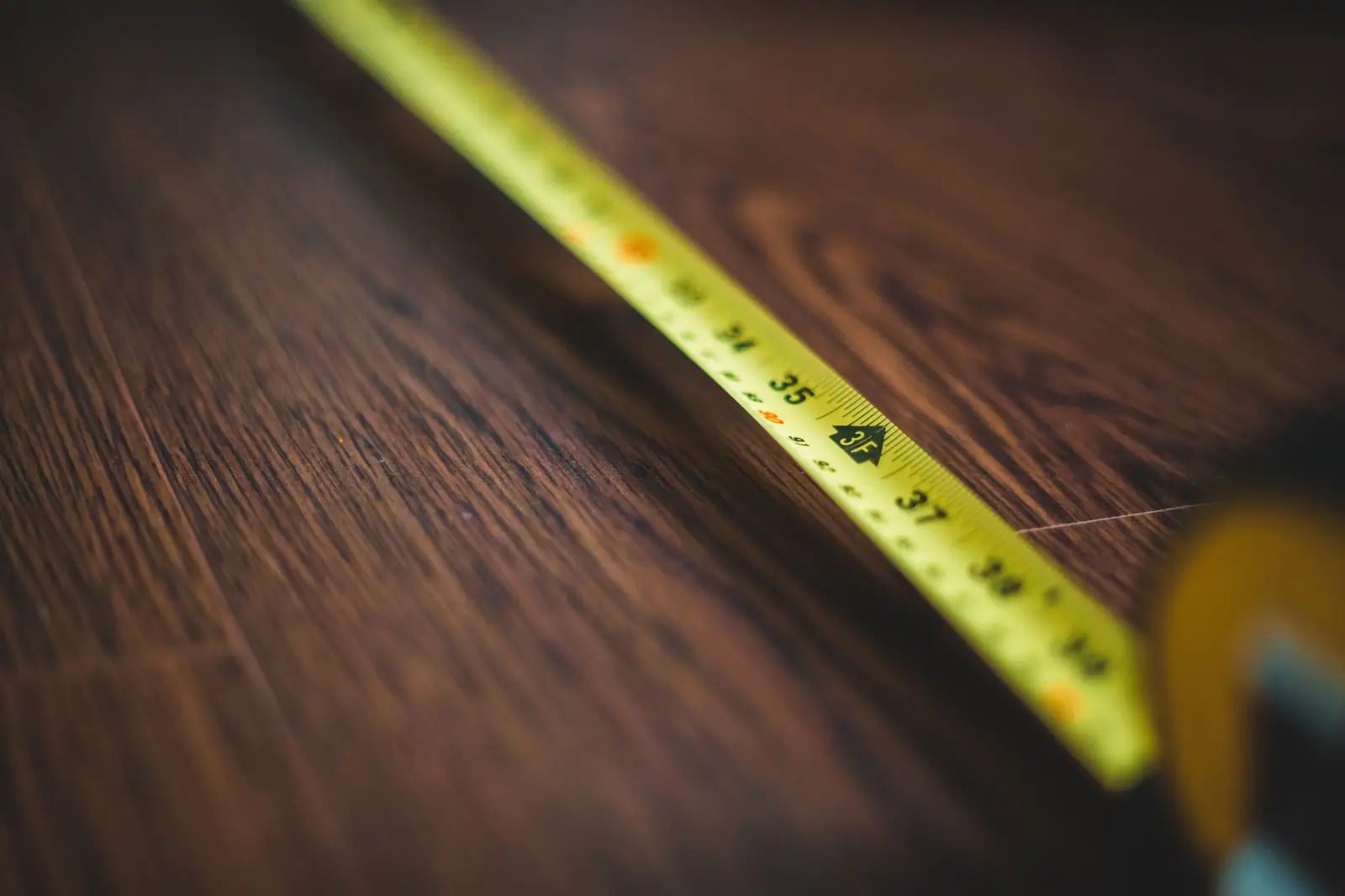 Yellow tape measure extended across a dark wood board
