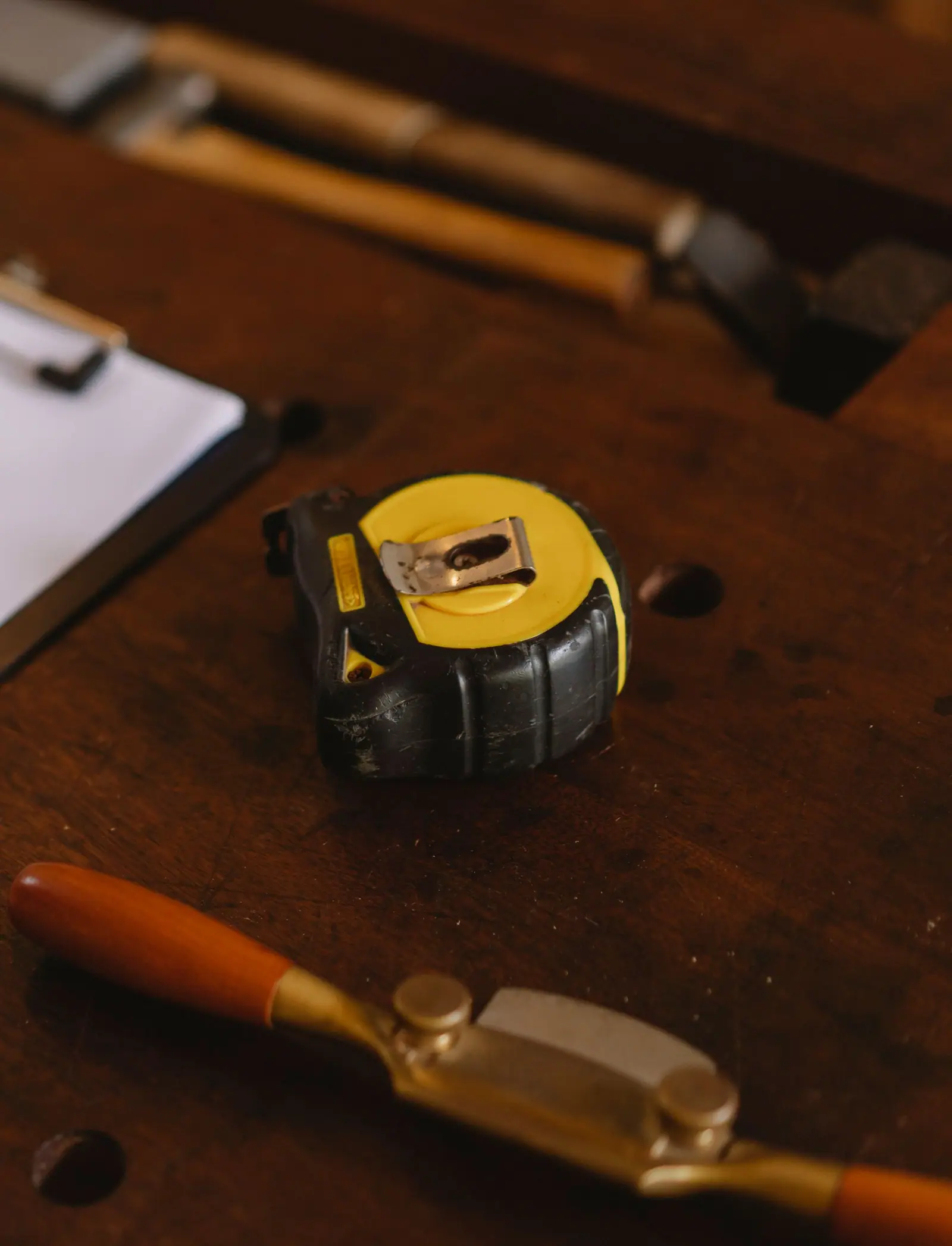 Tape measure, pencil and hand tools laid out on a wooden workbench